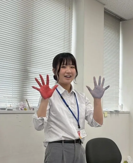 職場で両手を広げて笑顔を見せる大石さん