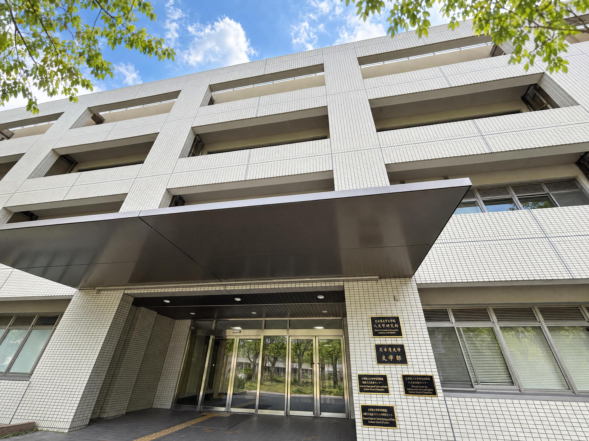 欅の葉越しに見上げた名古屋大学文学部の建物と入口